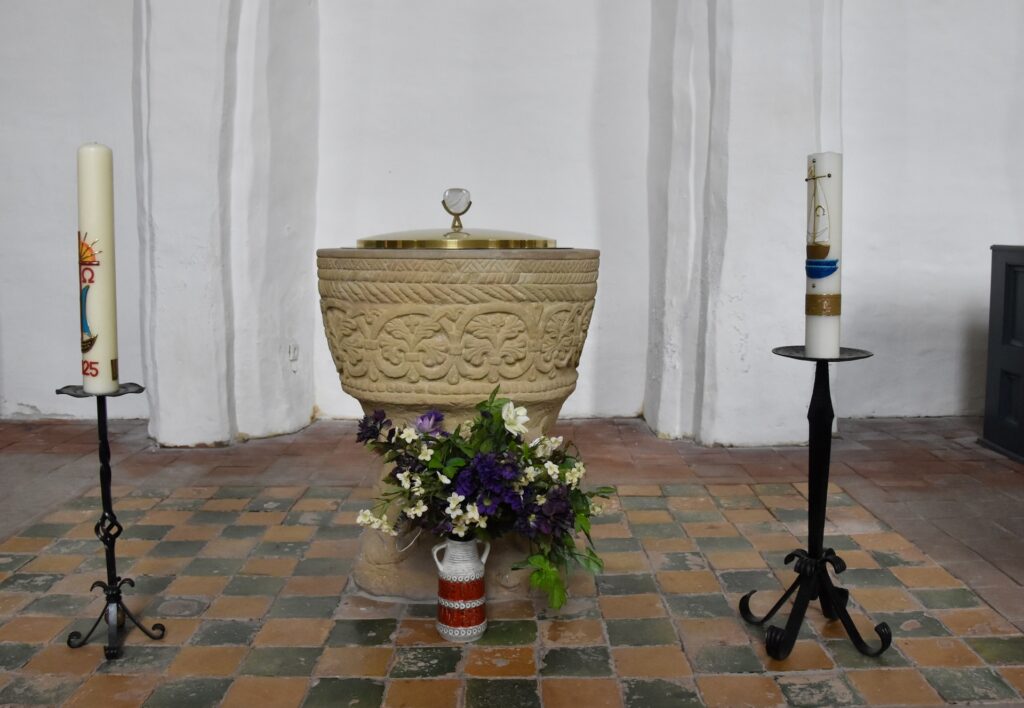 Die Taufe aus Sandstein – gefertigt um 1200 – ist ein Geschenk mit Umweg: Ursprünglich in Westerholt, kam sie in den 1960er Jahren nach Loquard. Restauriert von Willi Schmalstieg, ruht sie heute auf vier steinernen Löwen – und begeistert durch ihre schlichte Schönheit.